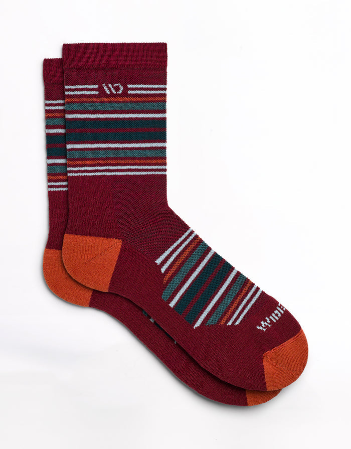 Socks laying flat with stripes on the cuff and over the top of the foot with red body and off white logo