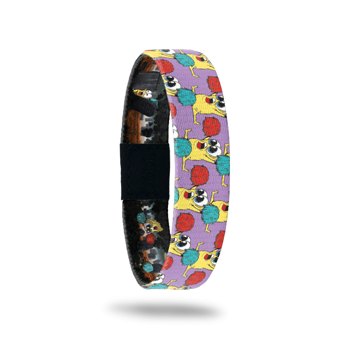 Product photo of the outside of 2021 - Day 1 - Rah Rah Ralph: purple background with repeating yellow monsters with big eyes doing a split while holding up a red and turquoise pom pom