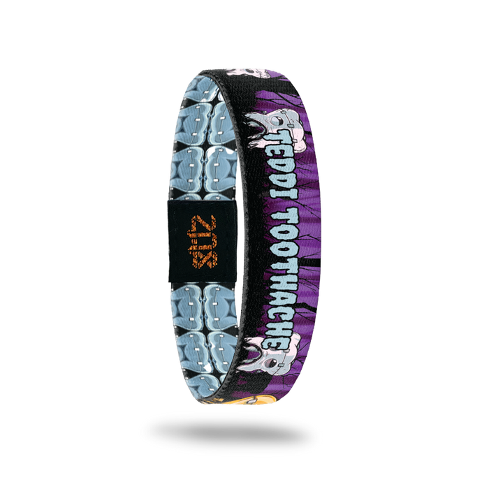 Product photo of the inside of 2021 - Day 13 - Toni Toothache: black and purple forest-like background with repeating white Frankenstein-like teeth with pouting faces. Light blue 'TEDDI TOOTHACHE' text.