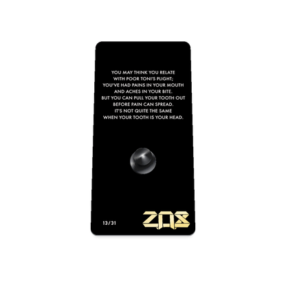 Product photo of the back of the collector’s of 2021 - Day 13 - Toni Toothache. It is a black background with white text ‘You may think you relate with poor Toni's plight; you've had pains in your mouth and aches in your bite. But you can pull your tooth out before pain can spread. It's not quite the same when your tooth is your head.'