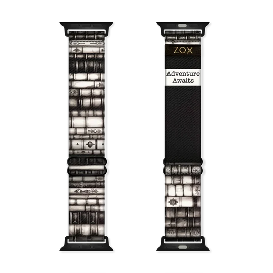 Watchband that is ornate books stacked on top of each other in various shades of black and white. The inside is the same and reads Adventure Awaits.