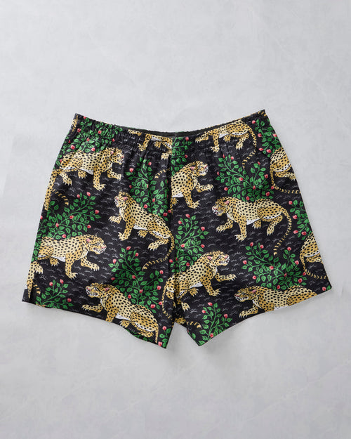 Ink boxer shorts laid flat with a spotted leopard, green foliage, and pink berry print