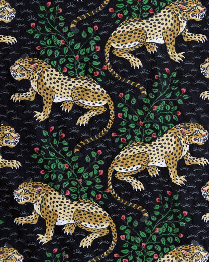 Close-up of the Bagheera print with spotted leopards, leafy branches, and red flowers on a black background