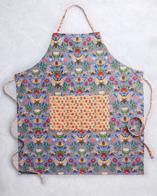 Bee-print apron laid flat, showing its adjustable neck strap, front pocket, and side ties.