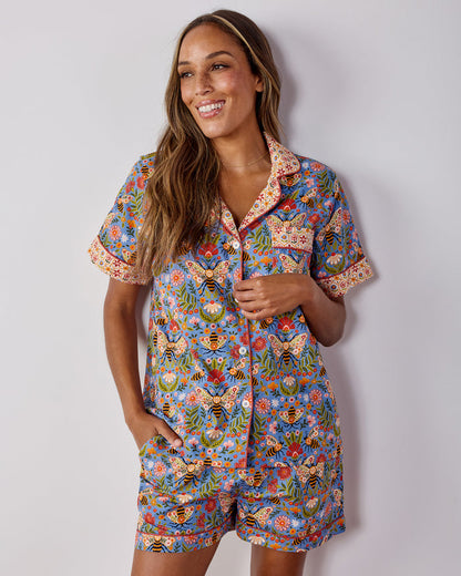 Model wearing the blue Bee Tapestry short pajama set with a button-front shirt and matching shorts.