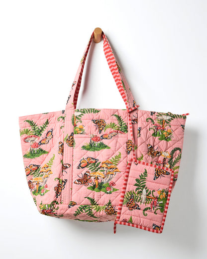 Rosewood quilted weekend bag with matching pouch, featuring butterflies, mushrooms, and ferns; the bag hangs from a wall peg.