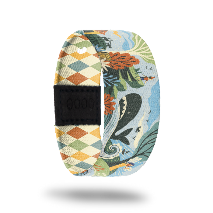 ZOX strap with cartoon design of little boy watching a whale in the ocean on the side of a mountain. Colors are muted orange, beige, blue and green. Comes with a matching pin and collector's box.