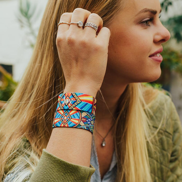 Lifestyle side portrait image of someone fixing their hair and wearing two Joy straps on one arm