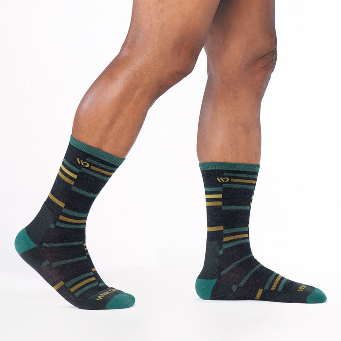 Model walking to the right wearing the 9010 crossroads cushioned crew in charcoal featuring teal heel/toe with yellow logo