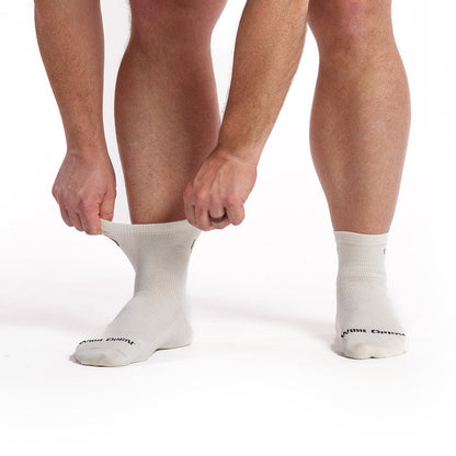 Models feet facing forward stretching the left cuff of the Men's 9014 Solid lightweight quarter sock in white