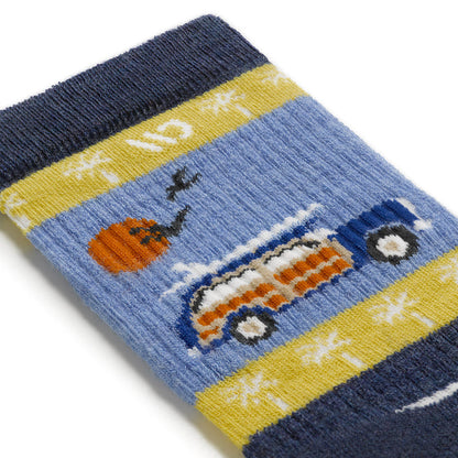 Detail image of the way back cuff featuring the Woody car with surf board on top with an orange sun and birds flying